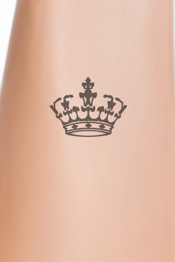 A profile view of a person showcases a temporary temporary tattoo on their shoulder, featuring a striking black and white illustration of a traditional crown. The crown has a circular band with intricate designs and a pointed top, embellished with small, stylized floral or leaf-like