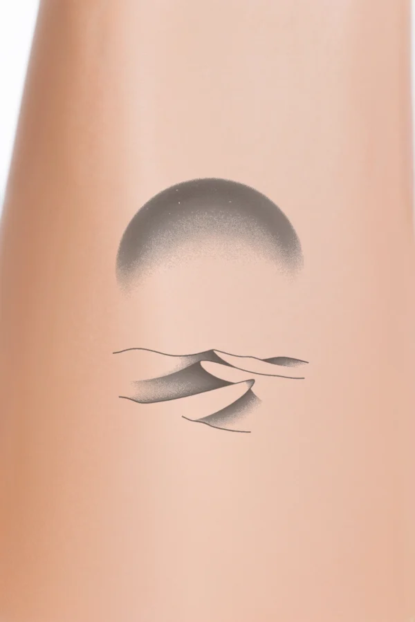 A striking black and white temporary temporary tattoo design featuring a stylized desert landscape. The central focus is a large circular shape symbolizing the sun, characterized by a dark outer edge that transitions to a lighter inner edge. The background is stark white, enhancing the