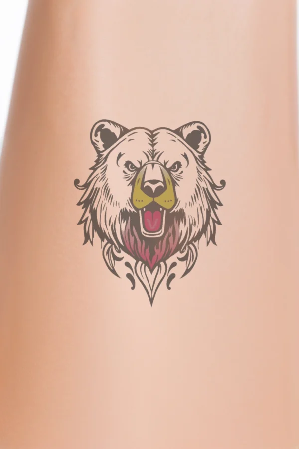 Close-up of a person's lower leg featuring a temporary temporary tattoo on the calf. The temporary tattoo displays a striking black and white illustration of a bear's head, with its mouth open in a roar and a pink tongue visible. The bear's eyes are wide and