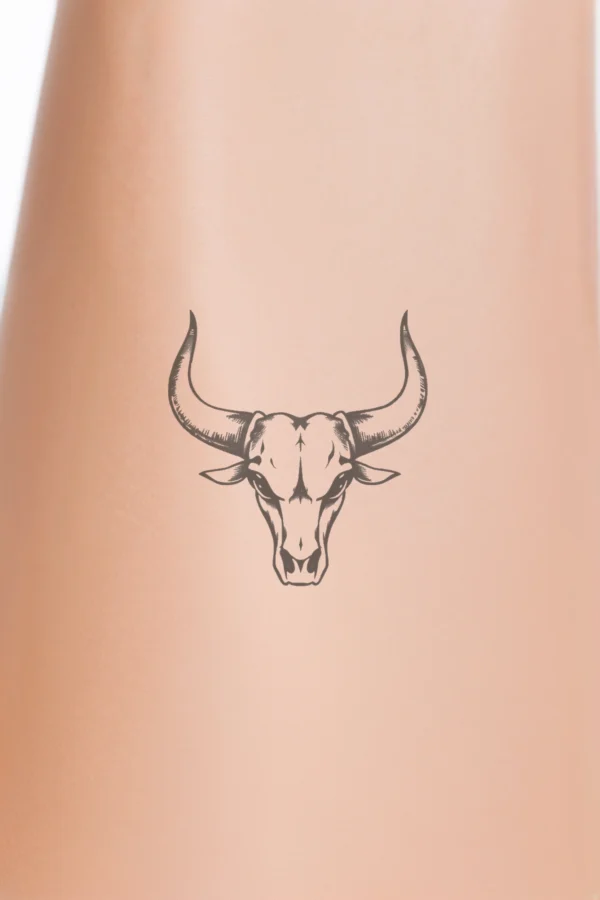 Temporary temporary tattoo design featuring a striking black and white illustration of a bull's head, facing forward with prominent, thick, curved horns. The bull's head is centered against a stark white background, emphasizing its strength and power as the sole focal point of the