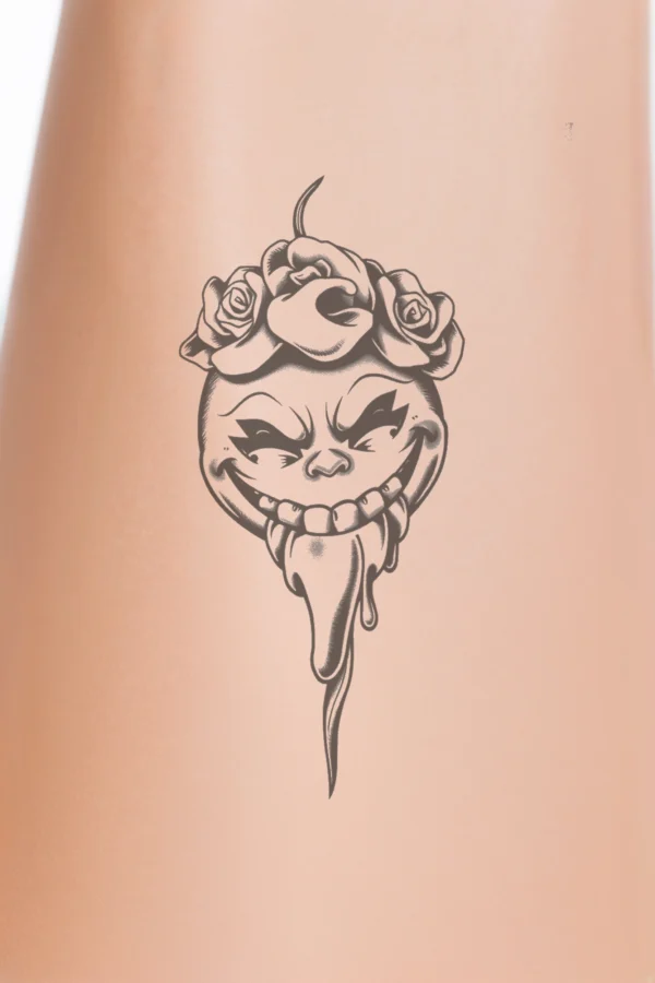A bold black and white temporary temporary tattoo design featuring a stylized face with exaggerated traits. The face is crowned with a cluster of roses atop the head, emphasizing a whimsical feel. It features a wide, open smile, a protruding tongue, and round