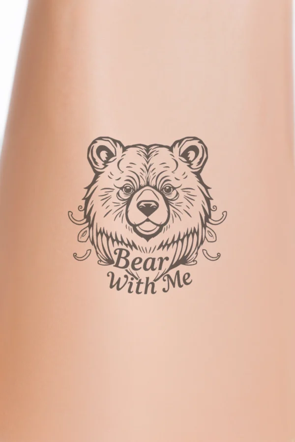 Close-up of a person's calf featuring a detailed black and white temporary tattoo of a bear's head. The bear's expressive eyes gaze directly at the viewer, while its prominent nose and slightly open mouth create a gentle smile. The fur is intricately illustrated with