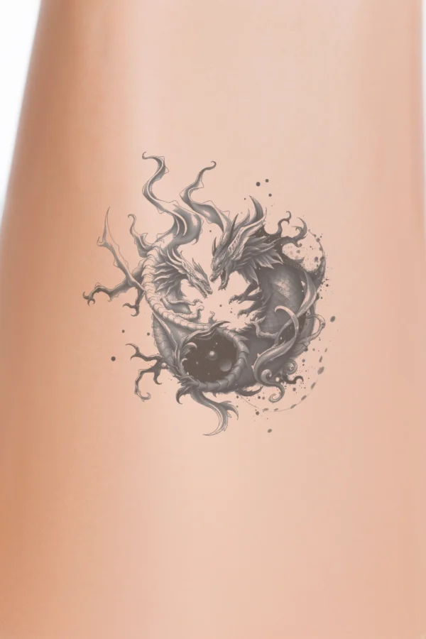 A striking temporary temporary tattoo design featuring a dragon in shades of black and gray. The dragon, positioned centrally and facing right, has a predominantly black body with gray accents and wings, while its mouth is a lighter gray. Its swirling, fiery tail adds a