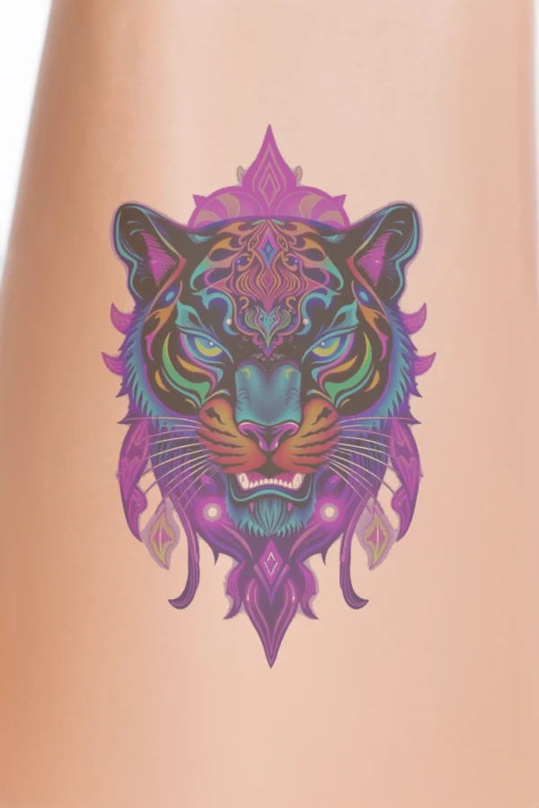 A vibrant temporary temporary tattoo illustration of a tiger's head, featuring a fierce expression with wide blue eyes and a slightly open mouth. The fur is styled in dynamic black and orange patterns with intricate designs, accented by a crown-like structure in pink and purple at