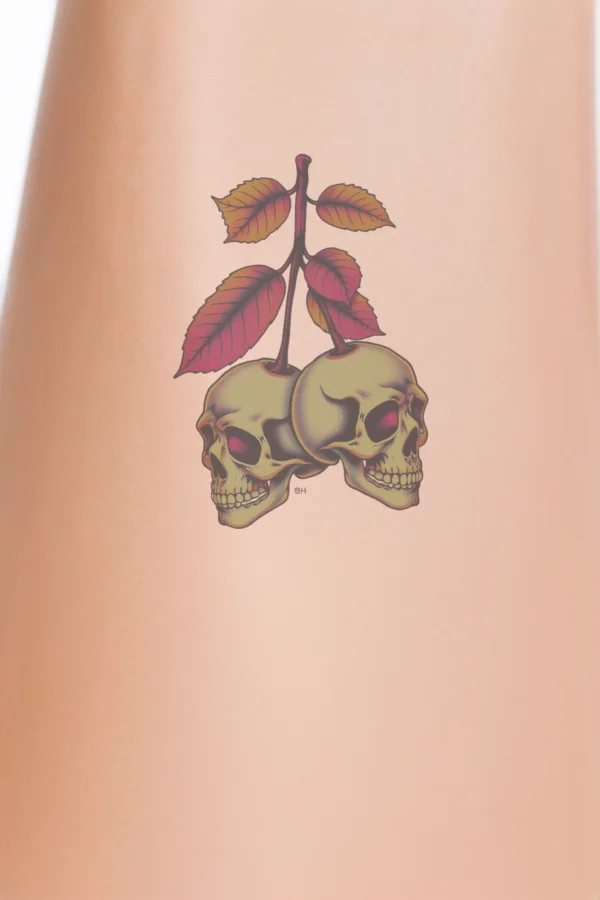 Alt text: "A temporary temporary tattoo design featuring two cream-colored skulls with vibrant pink, orange, and yellow accents, positioned symmetrically on either side of a central dark brown stem. The skulls face the same direction, creating balance, while