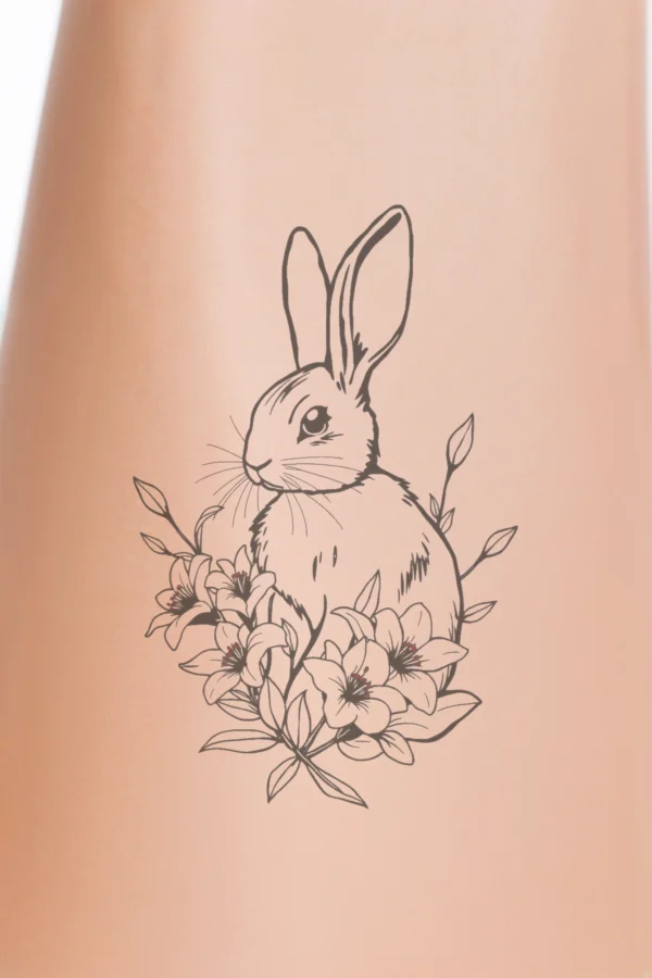 A black and white temporary temporary tattoo design featuring a textured rabbit at the center, facing right. The rabbit has a slightly turned head, large round eyes, a dark nose, and upright ears. It is surrounded by stylized flowers in white with touches of