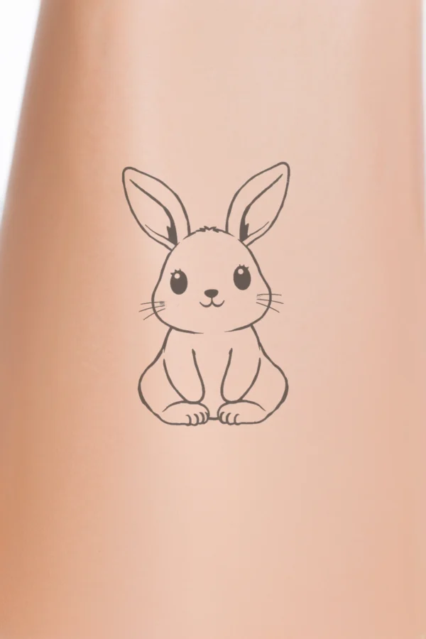 Temporary temporary tattoo design featuring a black and white illustration of a seated rabbit with tucked legs, large round ears, and a small round nose. The rabbit's fluffy fur is depicted in a simple, stylized manner against a blank background.