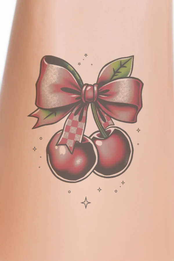 A vibrant temporary temporary tattoo design featuring two red cherries adorned with pinkish-red bows, centered in the image. The cherries have bold outlines and deep red coloring, with stems extending upwards, suggesting a floating appearance. The stark white background enhances their brightness, while