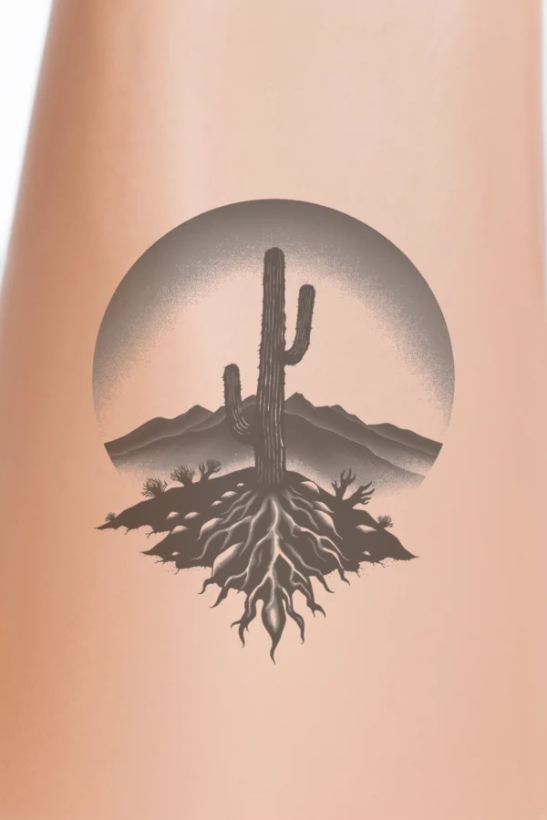 Temporary temporary tattoo design featuring a bold black and white illustration of a cactus at its center, characterized by spiny arms and lighter shaded roots extending downward. The cactus is framed by a circular border, enhancing the composition's symmetry. In the background, a desert